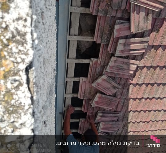 אדם מתקן רעפים על גג שבור